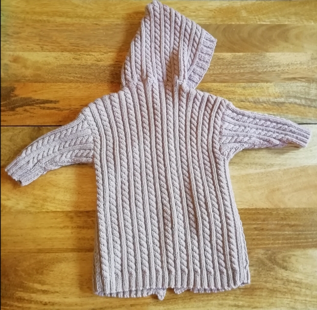 The back of a hooded cabled cardigan